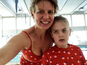 Ida and I wearing matching red bathing suits in an indoor pool.
