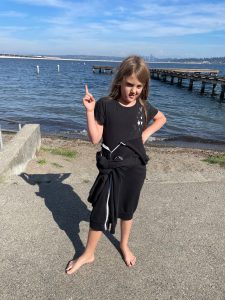 8 year old in black clothes standing in front of a lake