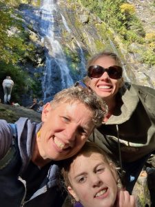 Three smiling people in front of waterfall